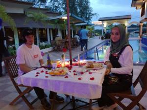 een man en een vrouw aan een tafel met eten bij Al Safina Kijal Beach Resort in Kijal