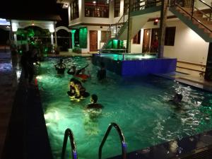 een groep mensen in een zwembad 's nachts bij Al Safina Kijal Beach Resort in Kijal