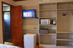 a room with a microwave and a tv on a wall at Residencial Aconchego do Lago in Gramado