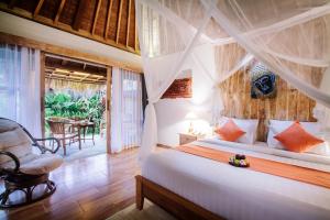 um quarto com uma cama e uma cadeira num quarto em Bije Suite Villa Ubud em Ubud