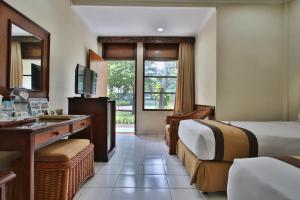 a hotel room with two beds and a desk at The Jayakarta Bali Beach Resort in Legian