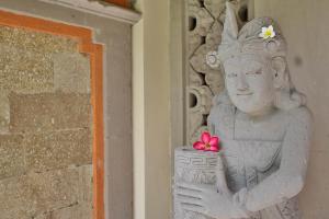 a statue of a woman holding a flower on a wall at The Jayakarta Bali Beach Resort in Legian
