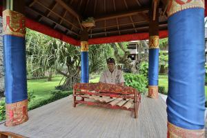 a man sitting on a bench on a porch at The Jayakarta Bali Beach Resort in Legian