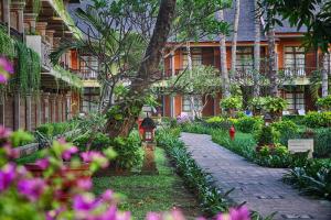 a garden in front of a building with flowers at The Jayakarta Bali Beach Resort in Legian