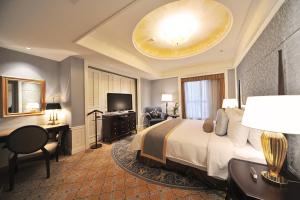 Habitación de hotel con cama, escritorio y TV. en Grand Central Hotel Shanghai en Shanghái