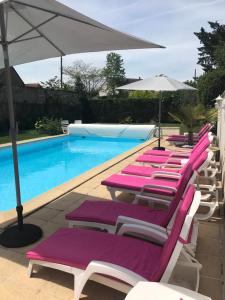 a row of lounge chairs next to a swimming pool at Logis Hotel Restaurant Le Cheval Blanc in Bléré