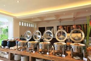 a buffet of food in metal pans on a table at Grand Palace Hotel Sanur - Bali in Sanur