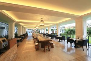 a restaurant with wooden tables and chairs and windows at Grand Palace Hotel Sanur - Bali in Sanur