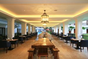 a restaurant with tables and chairs and a chandelier at Grand Palace Hotel Sanur - Bali in Sanur