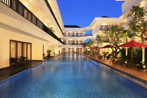 a swimming pool in a building with tables and chairs at Grand Palace Hotel Sanur - Bali in Sanur