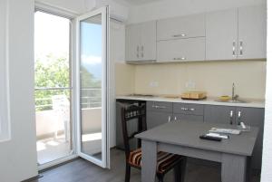 a kitchen with white cabinets and a table and a balcony at Madzar Apartments in Star Dojran