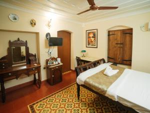 Schlafzimmer mit einem Bett, einem Schreibtisch und einem Spiegel in der Unterkunft Casa Menezes - A Heritage Goan Homestay in Bambolim