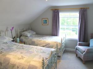 a bedroom with two beds and a chair and a window at Chalice Loft in Glastonbury