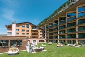 a large building with a yard with couches and chairs at Hotel Palü in Pontresina