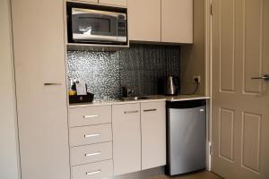 a kitchen with white cabinets and a microwave at Simmers Serviced Apartments in Williamstown