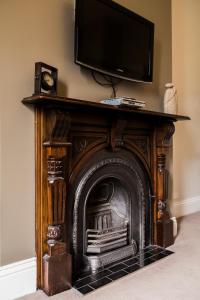 una chimenea con TV encima en Simmers Serviced Apartments, en Williamstown