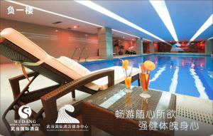 una piscina con 2 cócteles en una mesa junto a una piscina en Wudang International Hotel en Shiyan