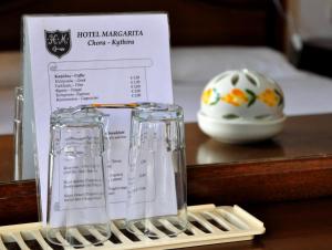 a table with two glasses and a menu and a vase at Margarita Hotel in Kythira