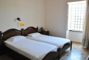 a bedroom with a bed with white sheets and a window at Margarita Hotel in Kythira