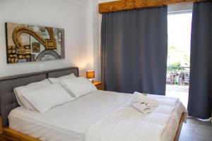 a bedroom with a white bed and a window at Hotel Hellas in Ancient Epidauros