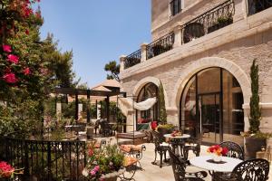 eine Außenterrasse mit Tischen, Stühlen und Blumen in der Unterkunft Villa Brown Jerusalem, a member of Brown Hotels in Jerusalem