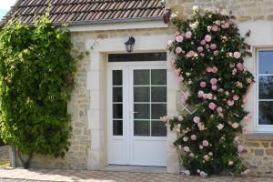 a house with a white door with pink roses at Chambres d'Hotes Elvire et Laurent Barbey in Sainte-Marie-du-Mont