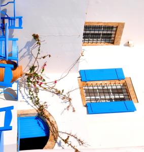 a building with blue windows and a plant at Margarita Hotel in Kythira