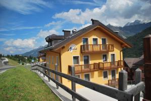 a yellow building with a balcony on a hill at Residence Hotel Anna in Passo del Tonale