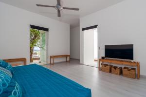 a bedroom with a blue bed and a flat screen tv at Bonaire Bay View Villa in Kralendijk