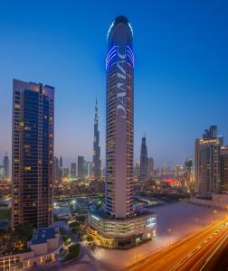 a large clock tower towering over a city at night at DAMAC Maison Distinction in Dubai