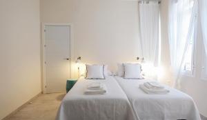 een witte slaapkamer met een groot bed met witte lakens bij CSE San Miguel in Sevilla