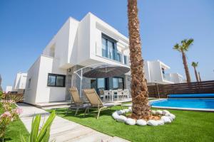 a villa with a palm tree and a swimming pool at Villa BALI 3033 in Vistabella