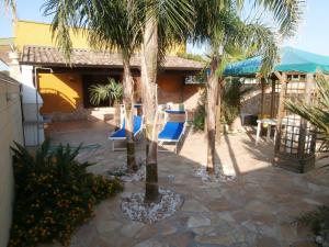 桑蒂西多羅的住宿－Villa Grandioso，庭院里种有棕榈树,摆放着蓝色的椅子