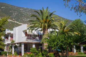 a building with palm trees in front of a mountain at Hotel Hellas in Ancient Epidauros