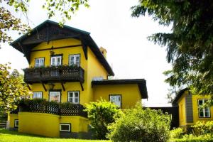 une maison jaune avec un balcon au-dessus dans l'établissement Ferienhaus Krieglach, à Krieglach