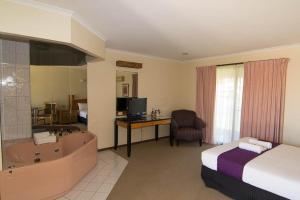 ein Hotelzimmer mit einem Bett und einer Badewanne sowie einem Schlafzimmer in der Unterkunft Balranald Motor Inn in Balranald