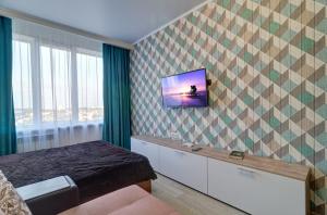 ペンザにあるApartment Novaya Prospekt Pobedy 96Eの壁にテレビが付いた客室で、ベッドが備わります。