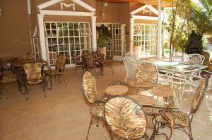 un patio al aire libre con mesas, sillas, mesas y ventanas en Falcon Crest Suites en Gaborone