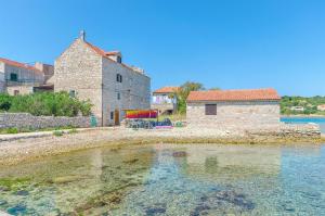 un bâtiment et une masse d'eau à côté d'un bâtiment dans l'établissement Apartments Islandbreeze, à Prvić Šepurine