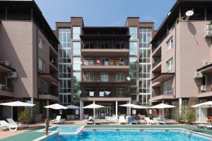 una persona in piedi vicino a una piscina di fronte agli edifici di Santa Sofia Studio a Sunny Beach