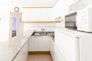 a white kitchen with white cabinets and a sink at Apartaments Fincasol in L'Estartit