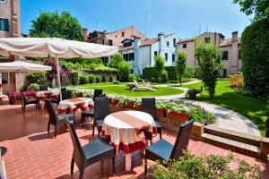 eine Terrasse mit Tischen und Stühlen sowie einen Garten in der Unterkunft Hotel Olimpia Venice, BW Signature Collection 3sup in Venedig