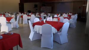 a room with white tables and red and white chairs at Pamo Hotel and Restaurants in Kitwe