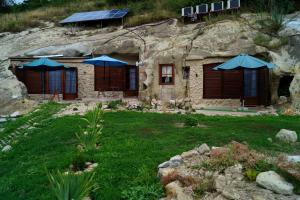 ein Steinhaus mit blauen Sonnenschirmen im Hof in der Unterkunft Sirocave barlang apartmanok in Sirok