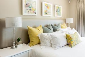 a bed with white pillows and pillows on it at Protea Point in Simonʼs Town