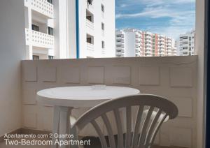 a table and a chair on a balcony with buildings at Akisol Portimão Beach II in Portimão