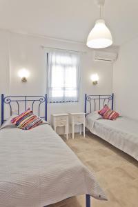 a bedroom with two beds and a table and a window at Alisachni Villas in Lefkos Karpathou
