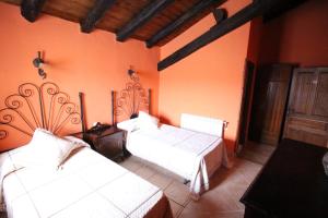 a bedroom with two beds and orange walls at Posada de Bielva in Bielva