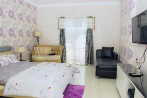 1 dormitorio con 1 cama, 1 silla y TV en Apartemen MTC en Manado