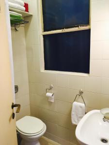 baño con aseo y lavabo y ventana en Casa Rosa en Buenos Aires